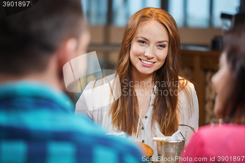 Image of happy woman dining with friends at restaurant