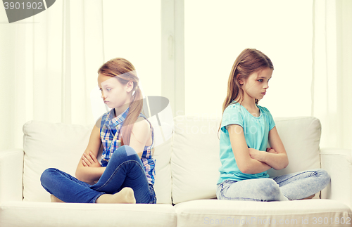 Image of quarreled little girls sitting on sofa at home