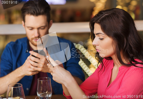 Image of couple with smartphones dining at restaurant
