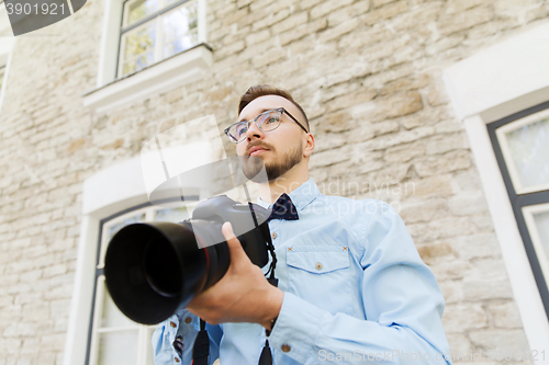 Image of young hipster man with digital camera in city