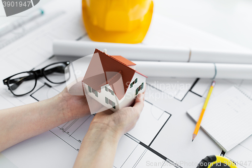 Image of close up of hands with house model above blueprint