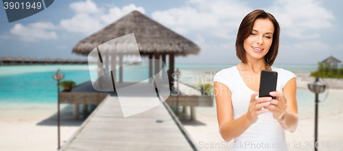 Image of happy woman taking selfie by smartphone over beach