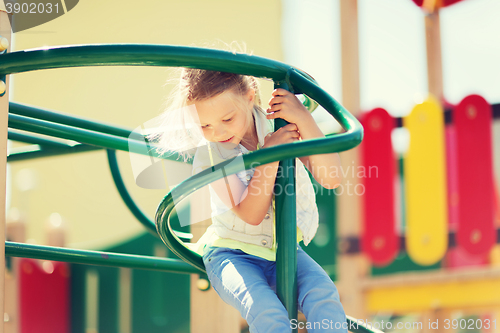 Image of happy little girl climbing on children playground