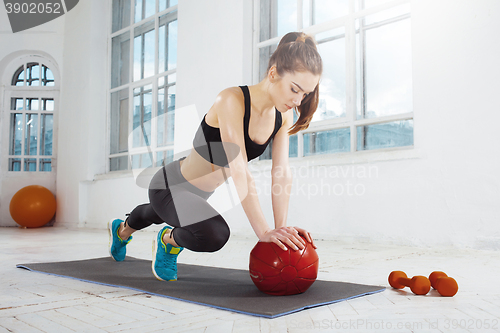 Image of Beautiful slim brunette doing some gymnastics at the gym