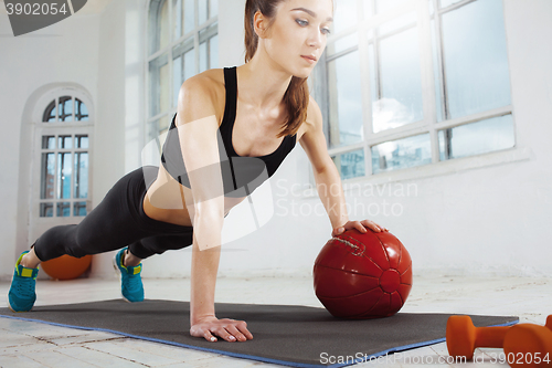 Image of Beautiful slim brunette doing some gymnastics at the gym