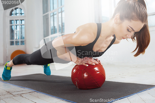 Image of Beautiful slim brunette doing some gymnastics at the gym