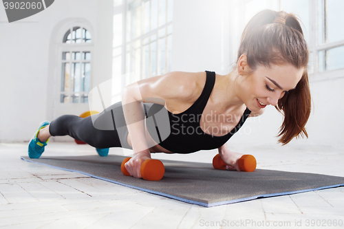 Image of Beautiful slim brunette  doing some push ups a the gym
