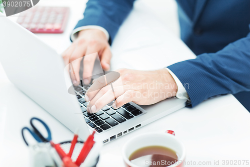 Image of The male hands on the keyboard of laptop computer