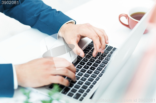 Image of The male hands on the keyboard of laptop computer