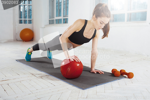 Image of Beautiful slim brunette doing some gymnastics at the gym