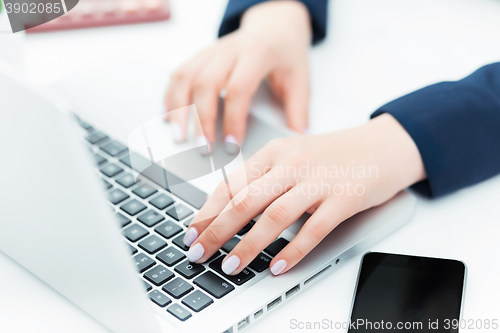 Image of The female hands on the keyboard of her laptop computer