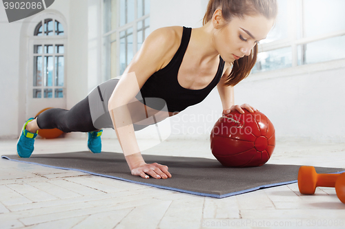 Image of Beautiful slim brunette doing some gymnastics at the gym