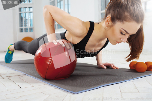 Image of Beautiful slim brunette doing some gymnastics at the gym