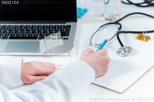 Image of The hands of doctor woman writing at the medical office