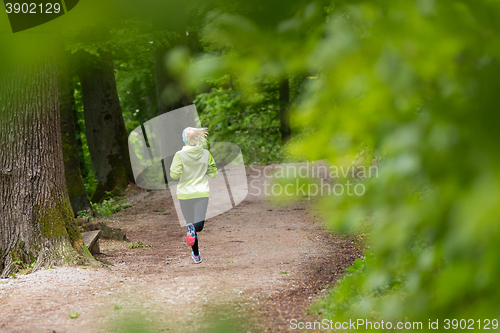 Image of Sporty young female runner in the forest. 