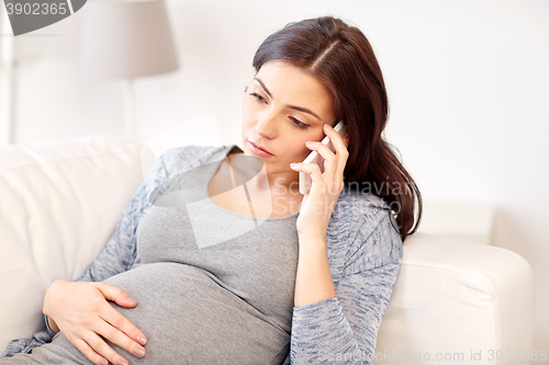 Image of sad pregnant woman calling on smartphone at home
