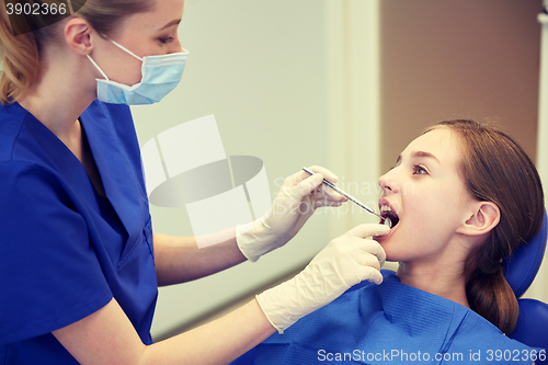 Image of female dentist checking patient girl teeth