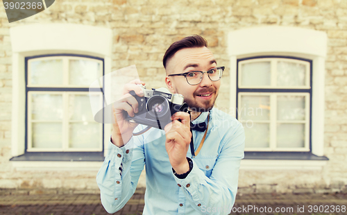 Image of happy young hipster man with film camera in city
