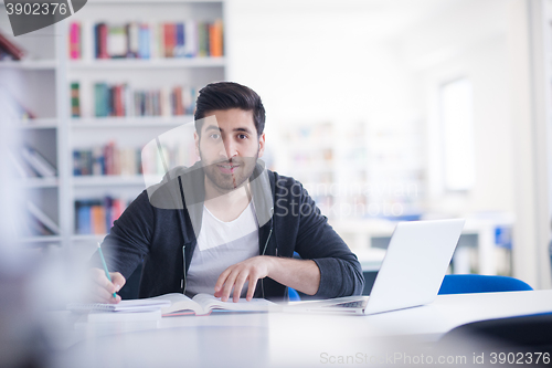 Image of student in school library using laptop for research