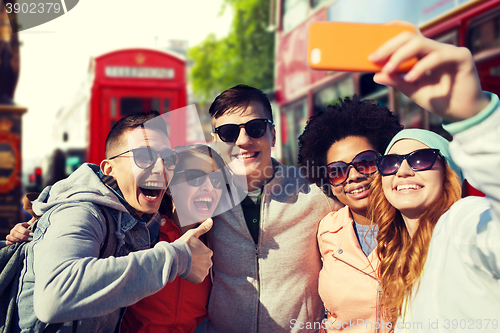 Image of smiling friends taking selfie with smartphone