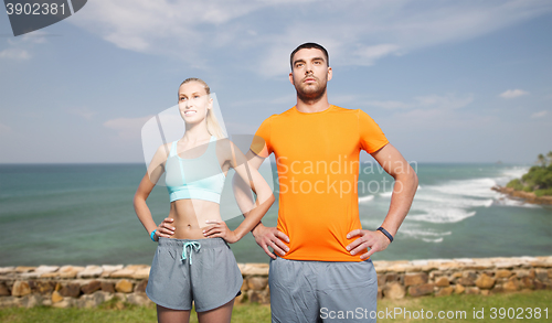 Image of happy couple exercising over sea or beach