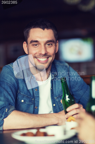 Image of happy young man drinking beer at bar or pub