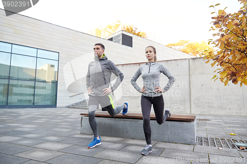 Image of couple doing lunge exercise on city street