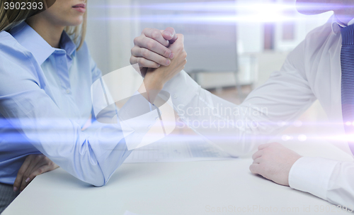 Image of businesswoman and businessman arm wrestling