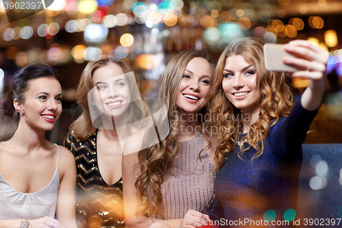 Image of women with smartphone taking selfie at night club