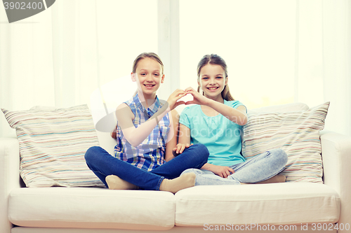 Image of happy little girls showing heart shape hand sign