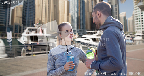 Image of smiling couple with bottles of water in city