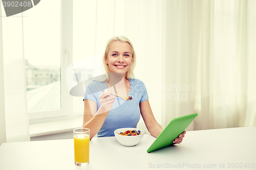 Image of woman with tablet pc eating breakfast at home