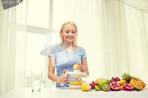 Image of smiling woman squeezing fruit juice at home
