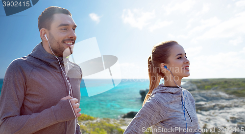 Image of happy couple with earphones running in city