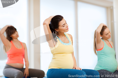 Image of happy pregnant women exercising on fitball in gym