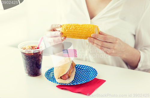 Image of woman hands holding corn with hot dog and cola