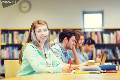 Image of happy student girl writing to notebook in library