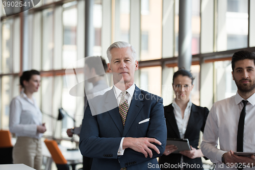 Image of portrait of senior businessman as leader  with group of people i