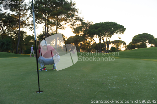 Image of golf player aiming perfect  shot on beautiful sunset