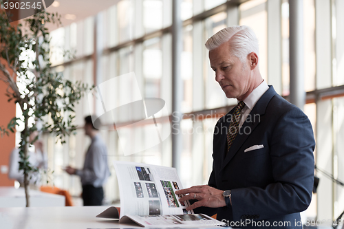 Image of senior business man reading magazine