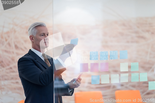 Image of senior business man making plans with sticker