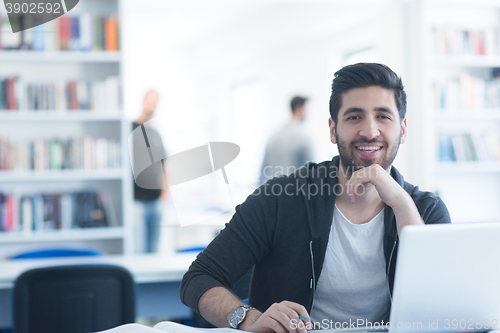 Image of student in school library using laptop for research