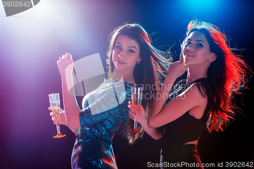 Image of Two beautiful girls dancing at the party drinking champagne