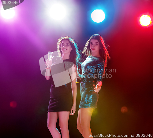 Image of Two beautiful girls dancing at the party drinking champagne
