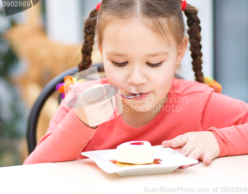 Image of Little girl is eating cake in parlor