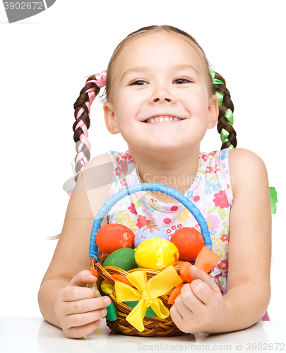 Image of Little girl with basket full of colorful eggs