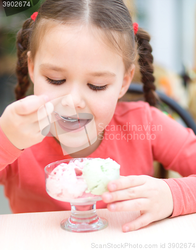 Image of Little girl is eating ice-cream in parlor