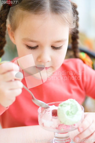 Image of Little girl is eating ice-cream in parlor