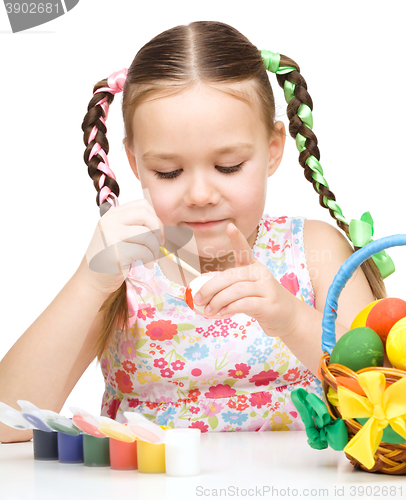Image of Little girl is painting eggs preparing for Easter