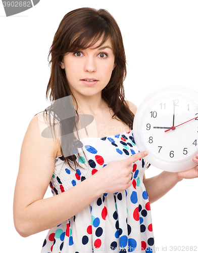 Image of Young woman is holding big clock